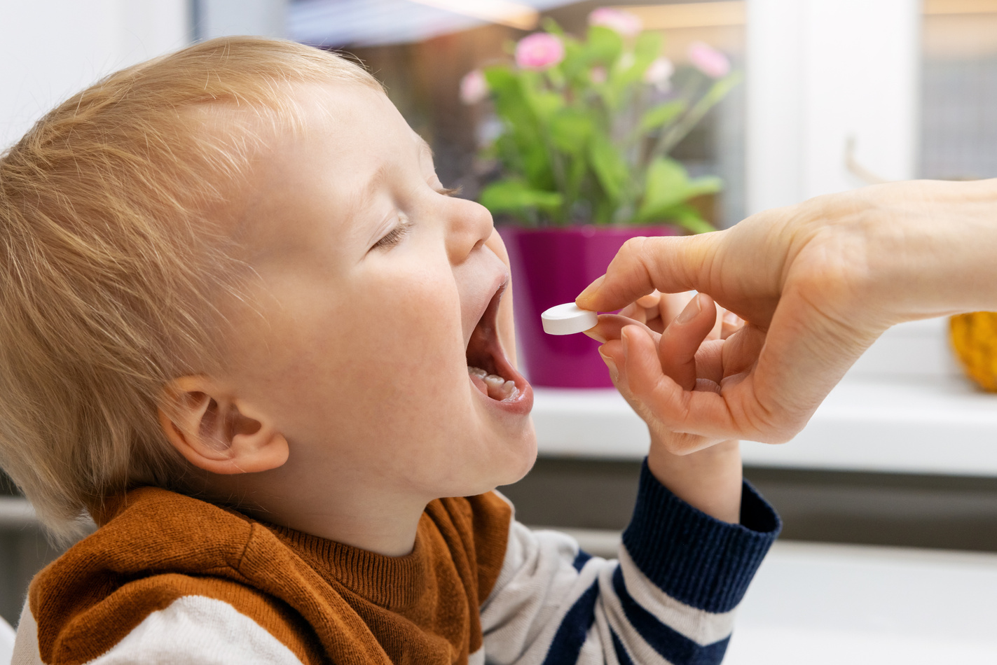 mother giving vitamin c pill to her child. dietary supplements for kids