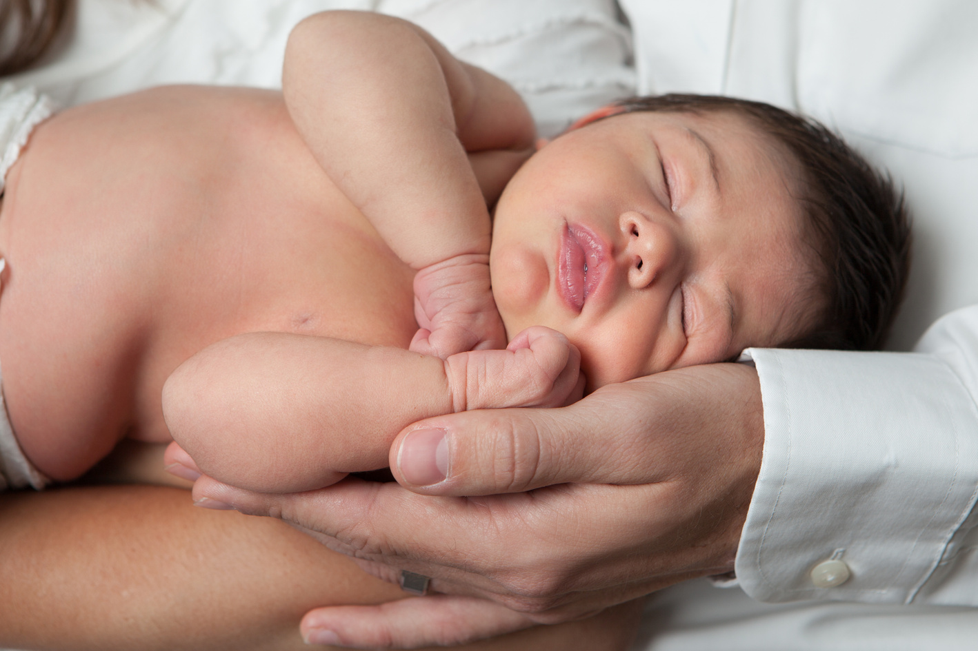 Newborn Baby Sleeping in Parents Arms